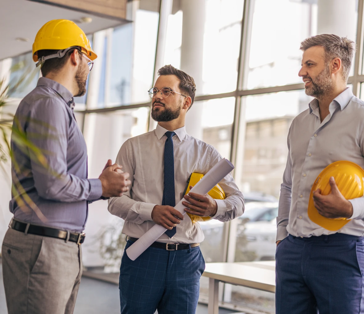 Three men discussing construction project indoors.