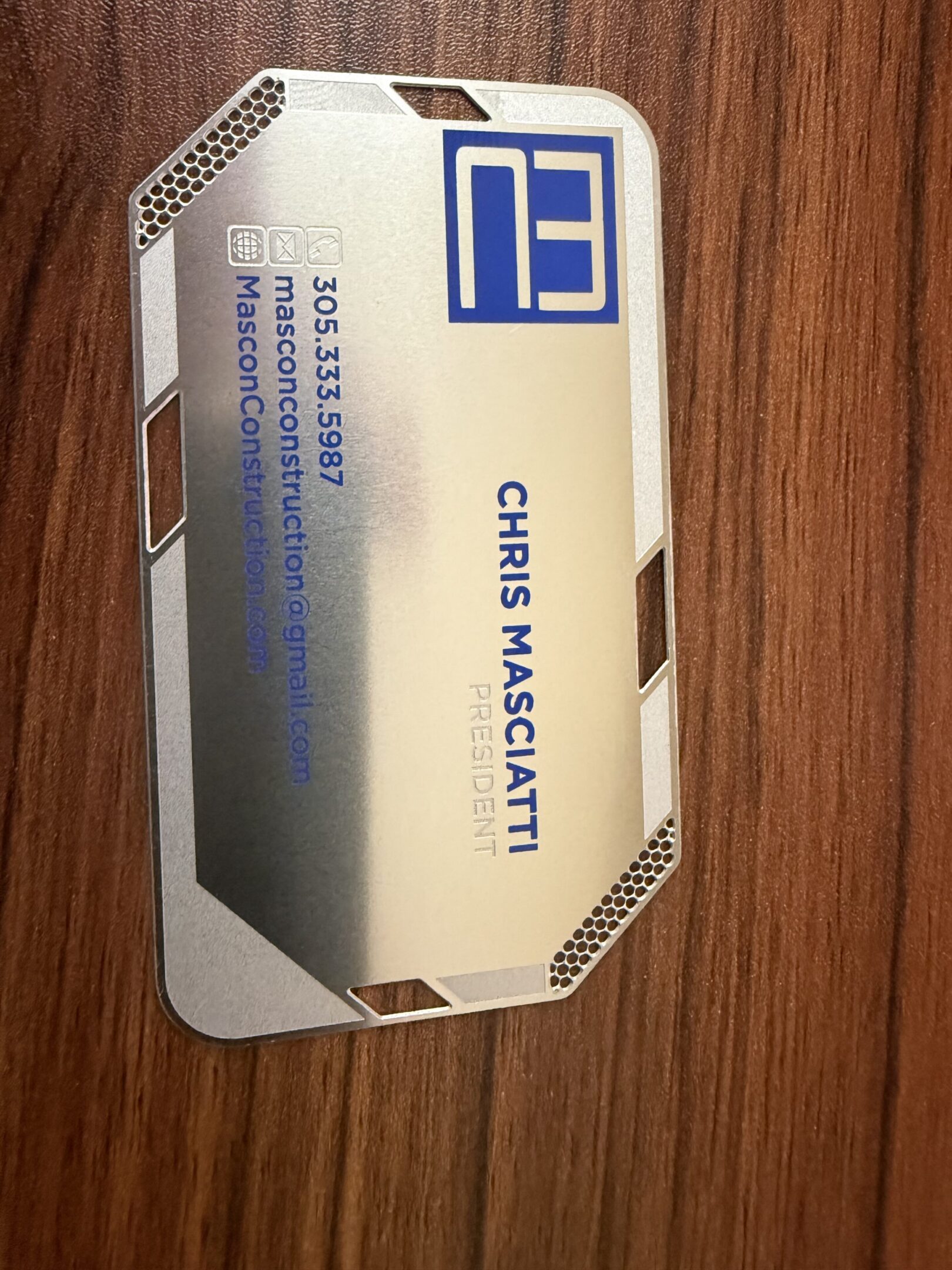 Metallic business card on wooden surface.