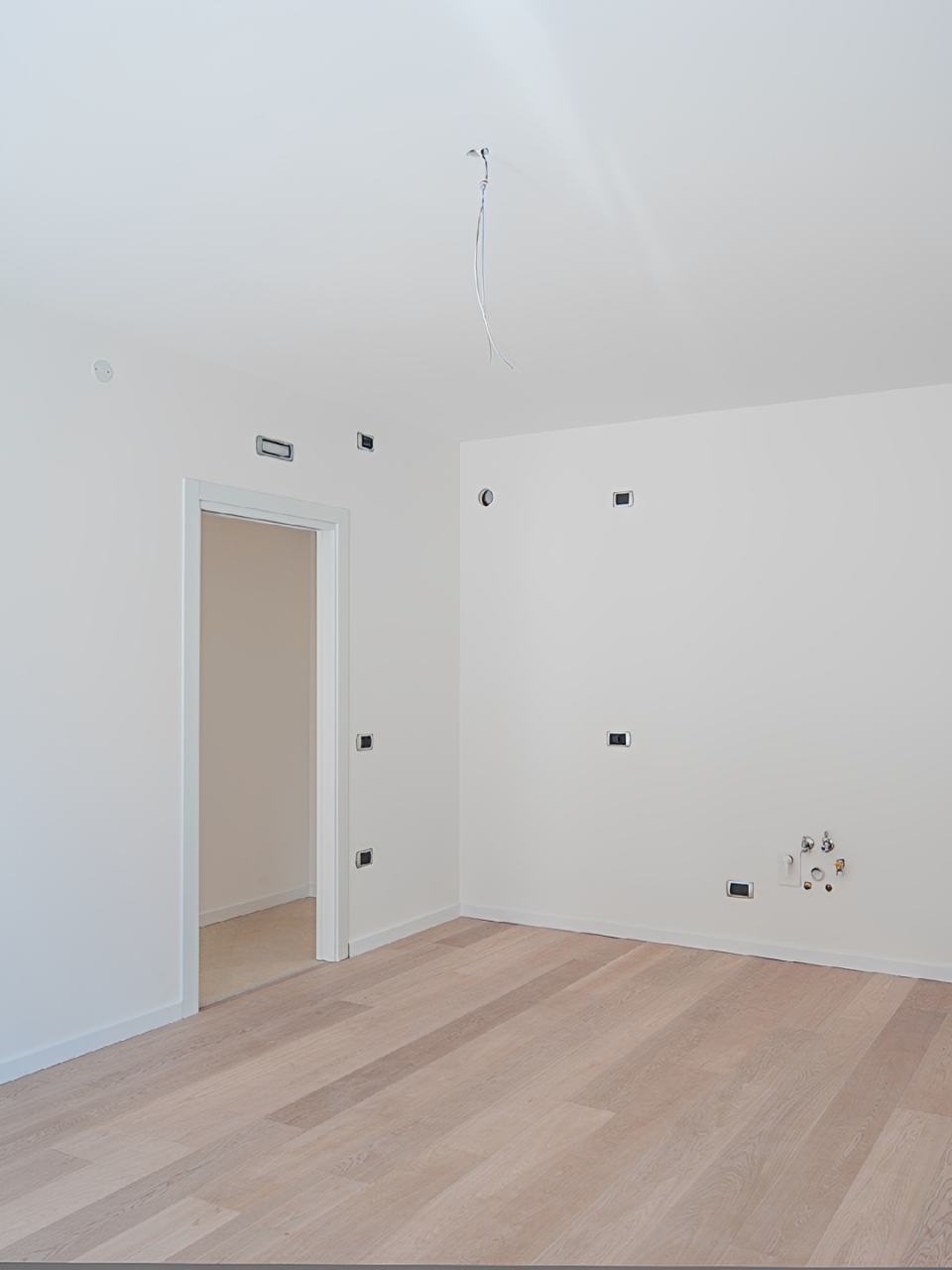 Empty room with wooden floor and doorway.